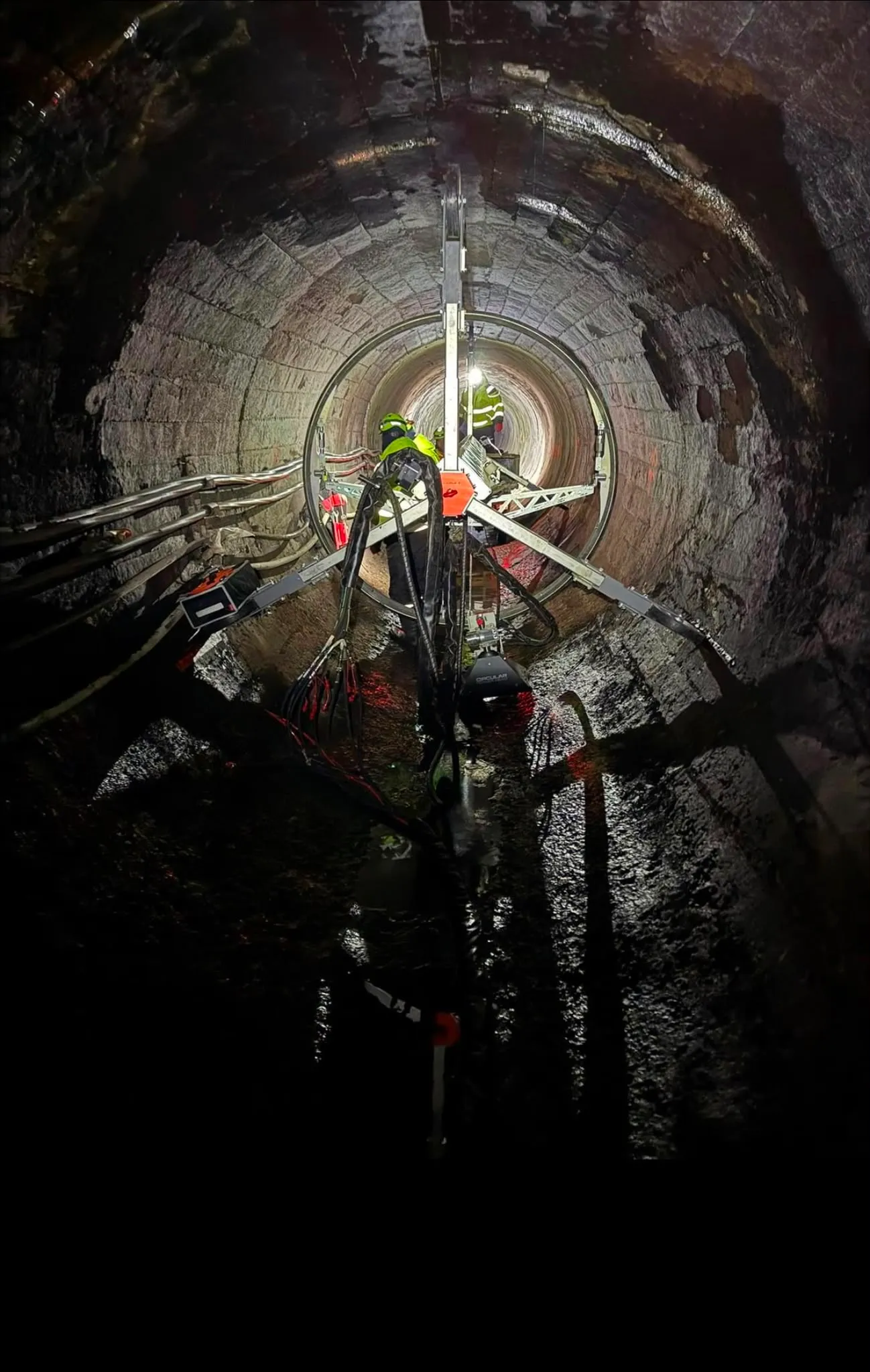 Arbejdshold dybt inde i en tunnel med en stjerneformet rig spændt op mod tunnelvæggen.