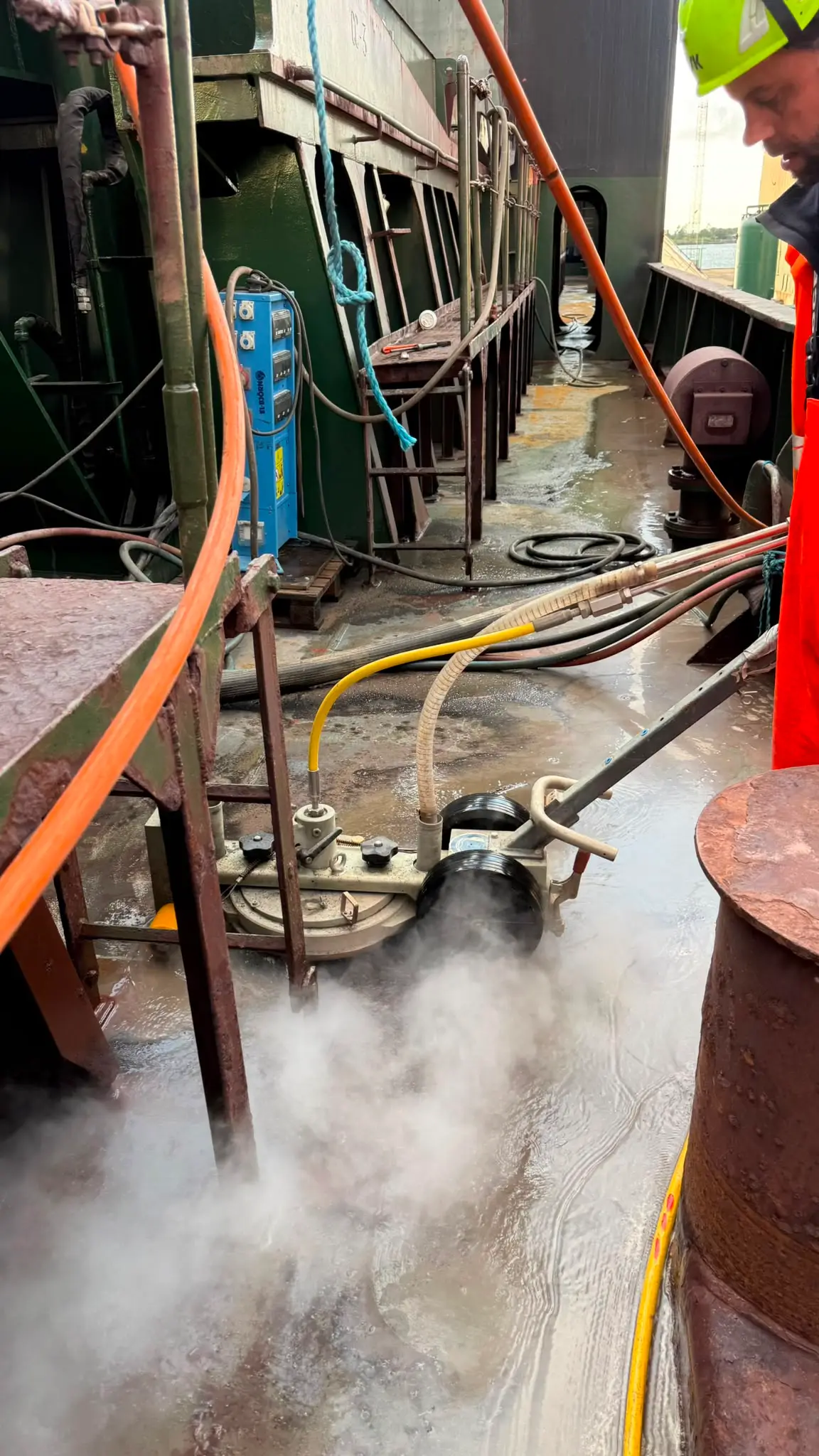 UHP-fladeværktøj i arbejde på et skibsdæk med damp fra vandstrålen.